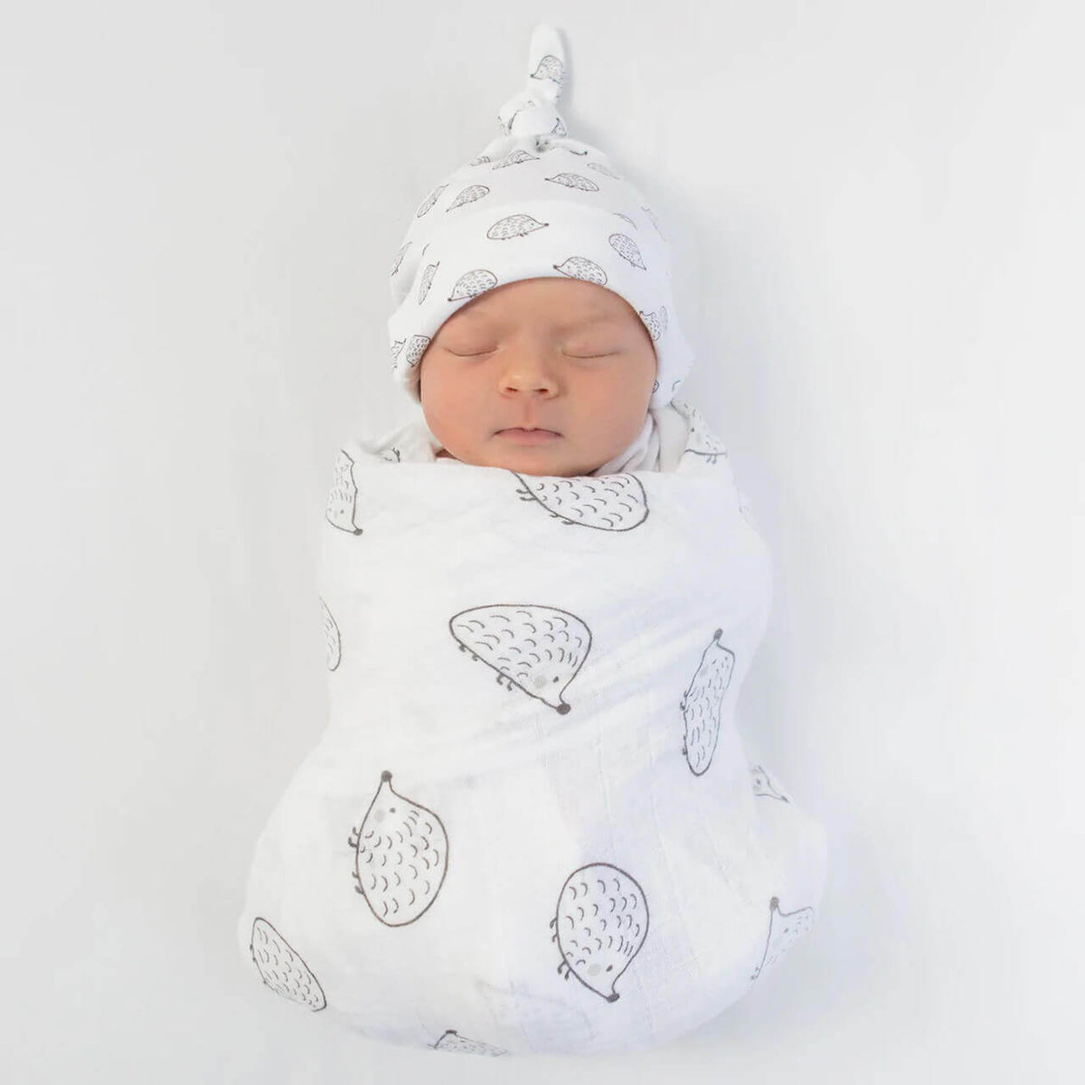 Swaddled newborn baby wrapped snugly in a white muslin blanket