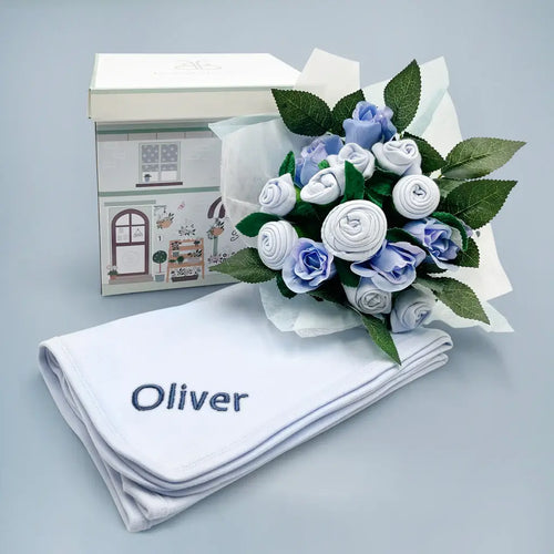Personalized baby boy gift set with blue baby clothing bouquet, embroidered white blanket, and illustrated gift box