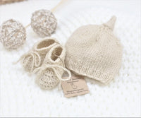 Handmade natural baby alpaca knotted cap and bootie set, flat lay, newborn size, gender neutral
