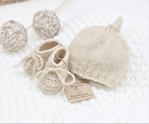 Handmade natural baby alpaca knotted cap and bootie set, flat lay, newborn size, gender neutral
