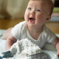 Baby enjoying tummy time with a plush dot lovey blanket