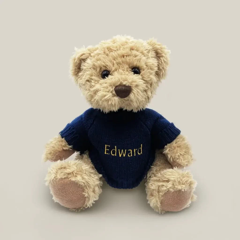 Front of Christmas teddy bear with baby's name personalized on a navy knitted sweater