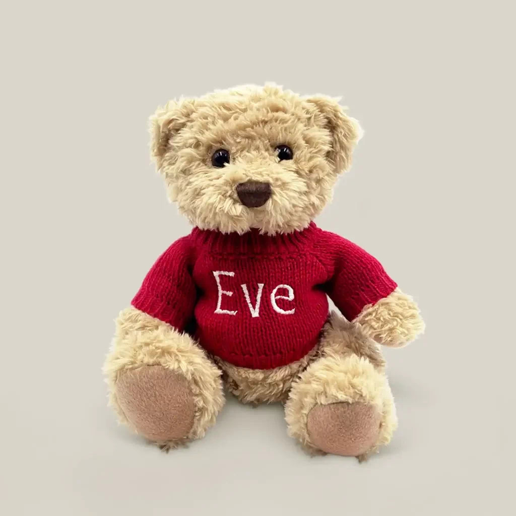 Front of Christmas teddy bear with baby's name personalized on a red knitted sweater