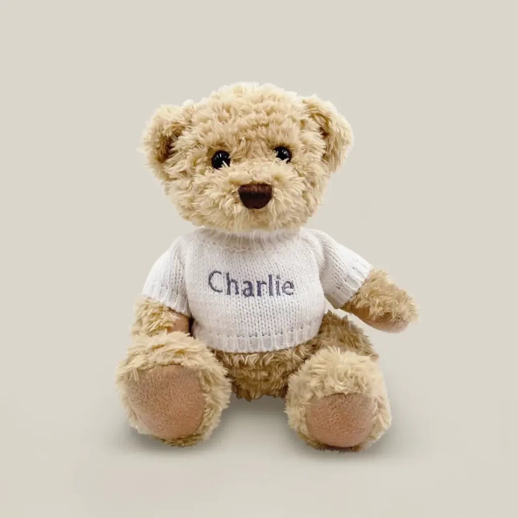 Front of Christmas teddy bear with baby's name personalized on a white knitted sweater