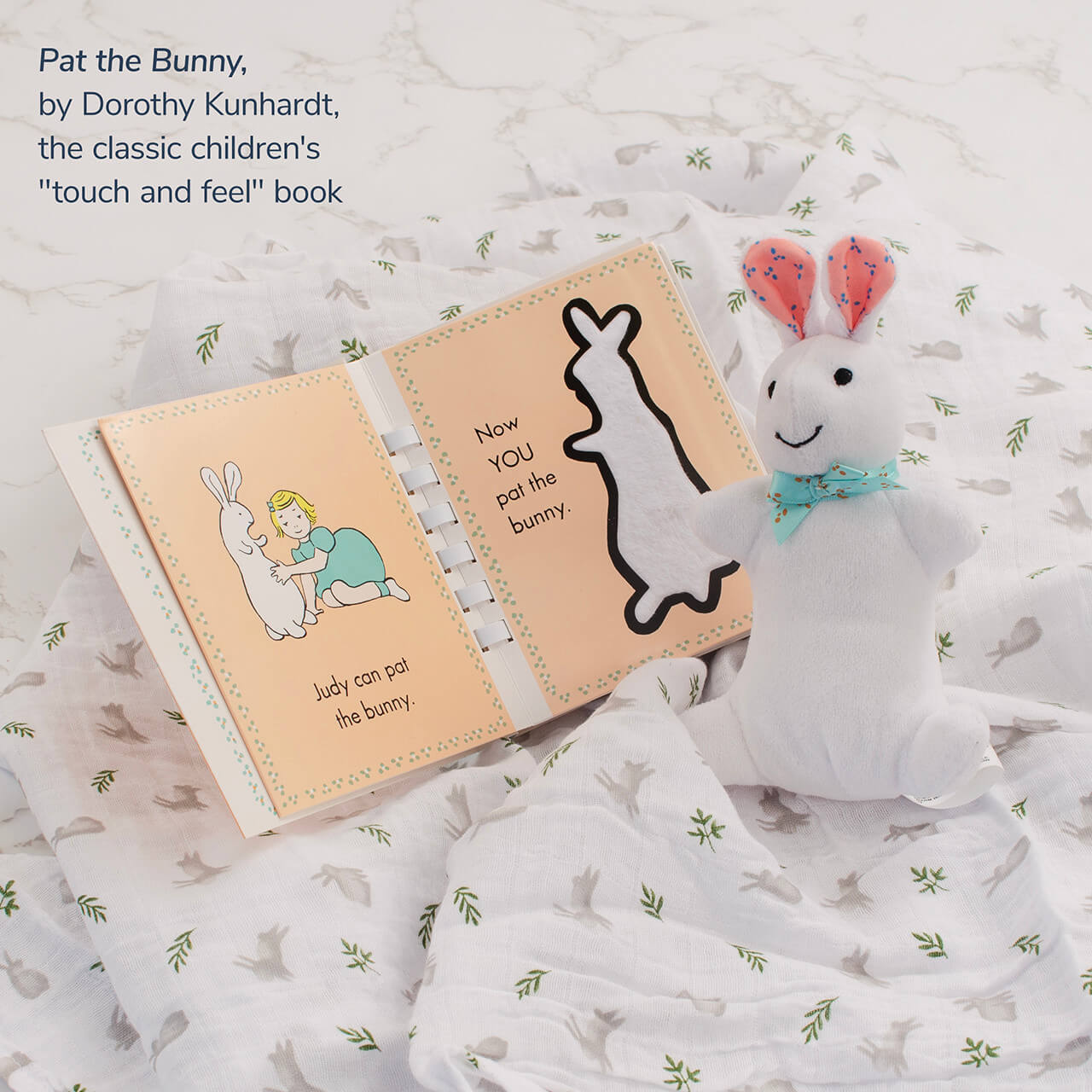 Close-up of Lulujo muslin swaddle blanket, Pat the Bunny book, and plush white bunny from The Little Bunny Welcome Set