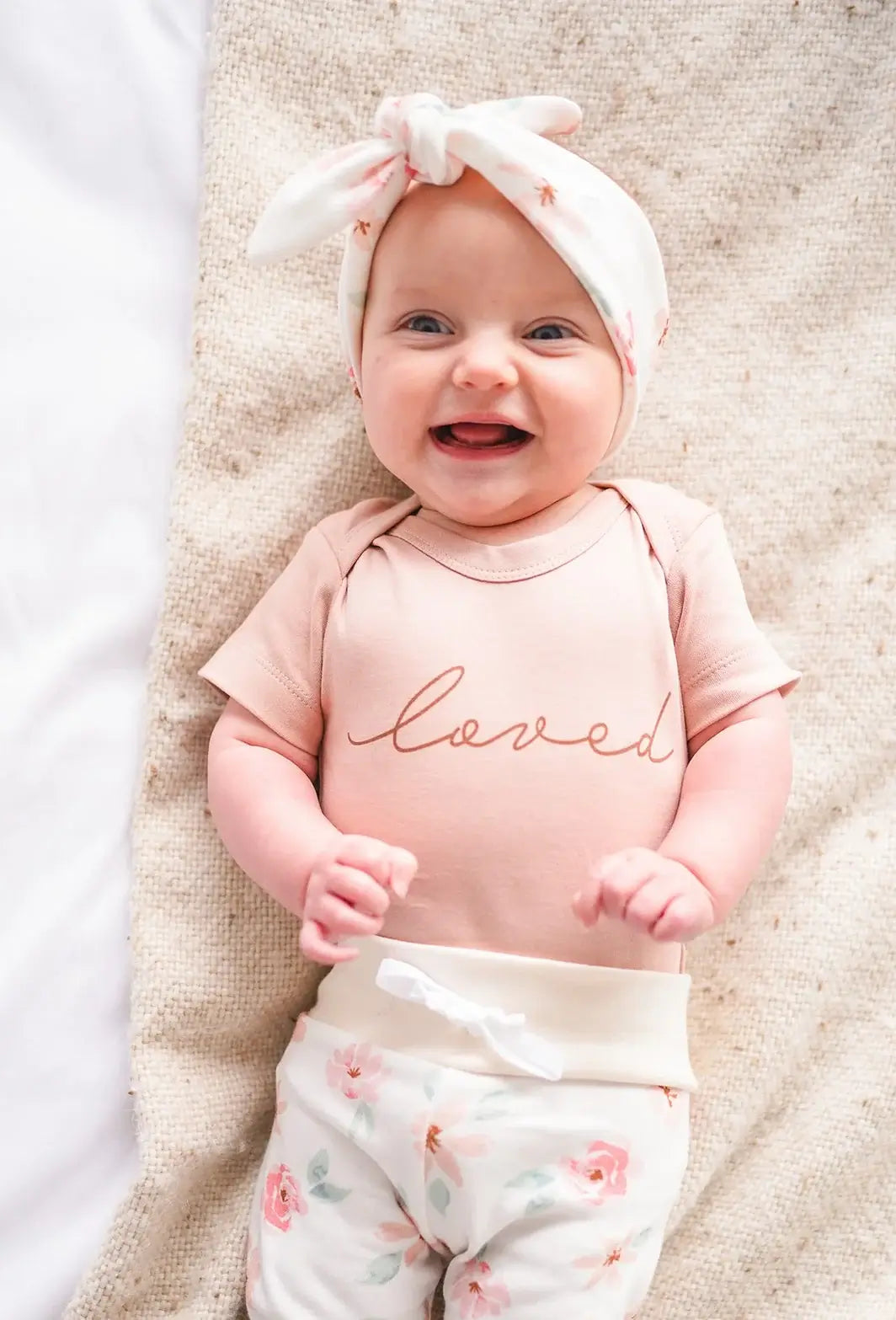 Newborn baby girl in mauve organic outfit from Stork Baby Gift Baskets