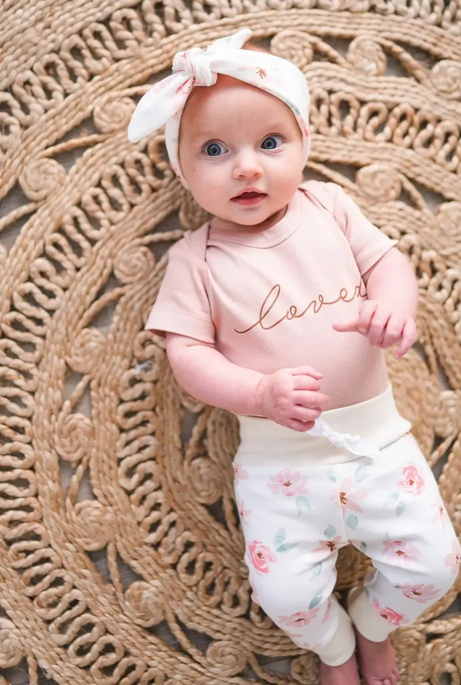 Baby girl wearing mauve organic layette set with floral leggings and headband