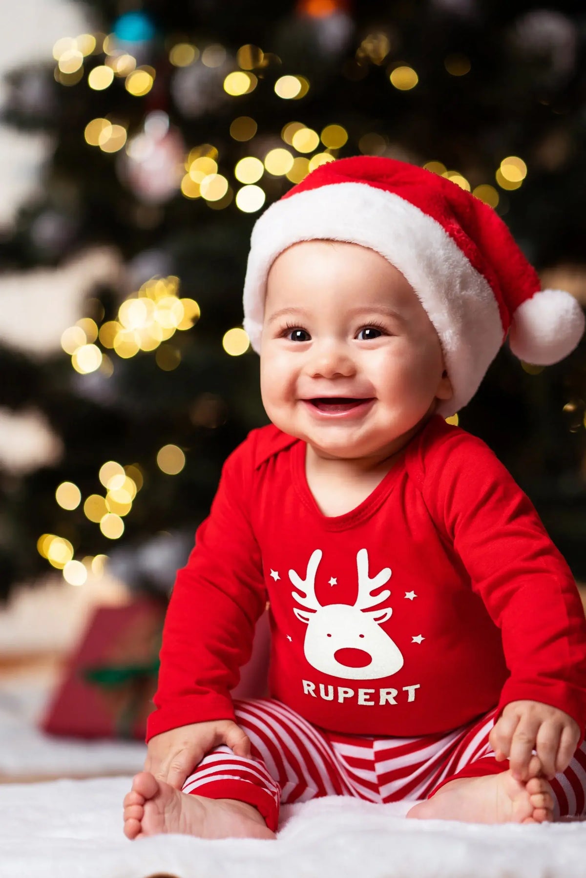Baby boy wearing a personalized red Christmas reindeer t-shirt and Santa hat