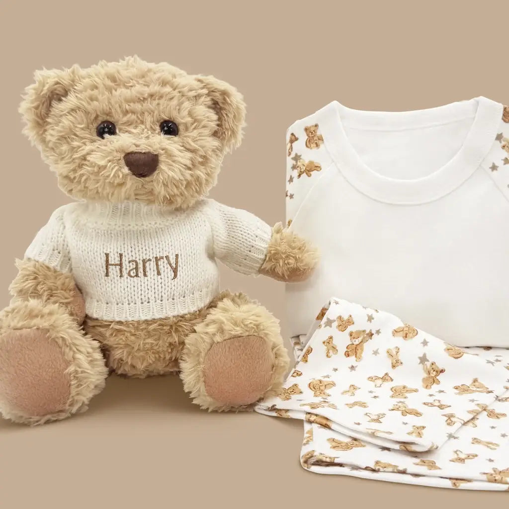 Personalized white knit sweater teddy bear with embroidered name alongside teddy bear print baby pajamas in illustrated gift box