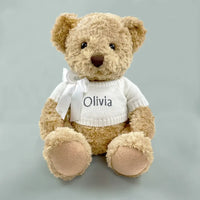 Personalized baby teddy bear keepsake gift in white knit sweater with embroidered name and white ribbon bow — neutral gray