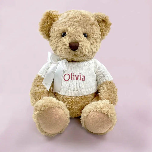 Personalized baby girl teddy bear in white knit sweater with pink embroidered name and white ribbon bow