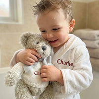 Toddler with wet hair wearing a personalized cotton bathrobe and snuggling a personalized teddy bear