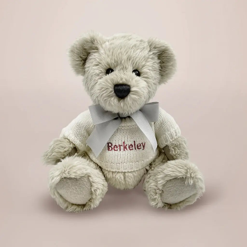 Personalized teddy bear in a white knitted sweater embroidered with baby's name in red